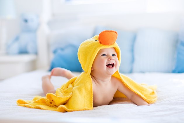 Funny cute baby after bath in yellow duck towel