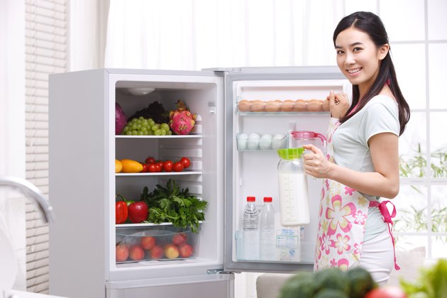 Young woman holding milk in kitchen
