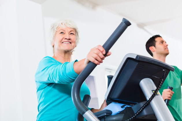 Senior woman on elliptical trainer exercising in gym