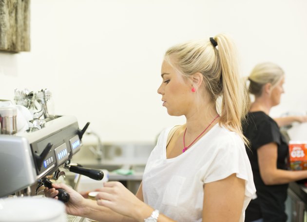 Young female barista making coffee in cafe