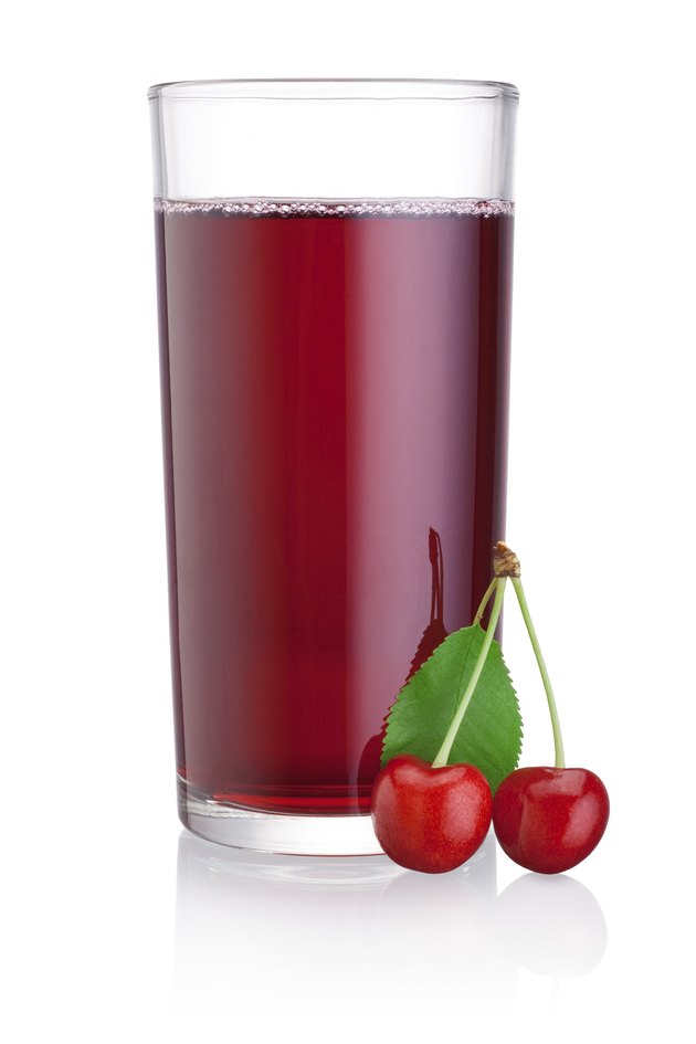 Glass of cherry juice with fruits isolated on white background