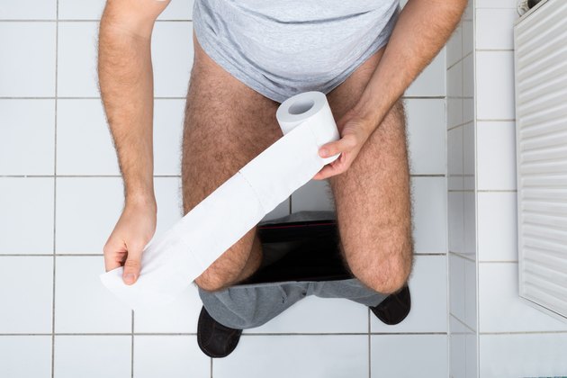 Man In Toilet Holding Tissue Paper