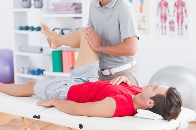 Physiotherapist doing leg massage to his patient