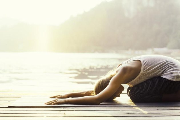 Beautiful woman practicing Yoga by the lake - Sun salutation series - Balasana or child's position - Toned image