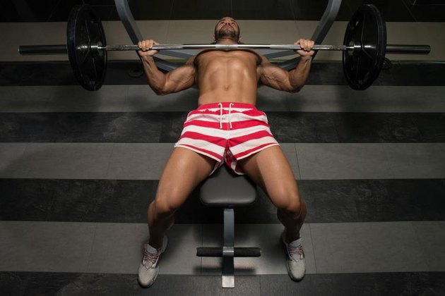 Young Man In Gym Exercising Chest On The Bench Press