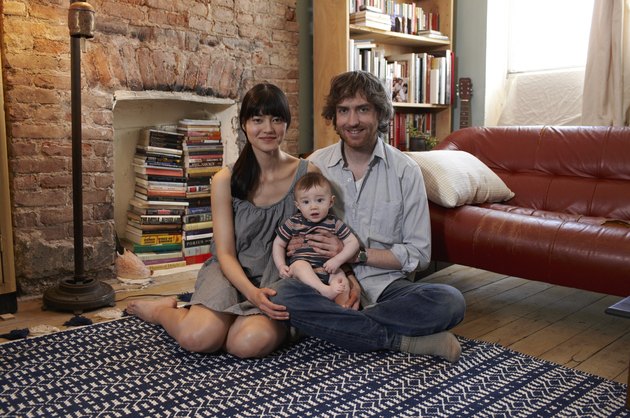 Parents with baby boy (6-11 months) sitting on carpet, smiling, portrait