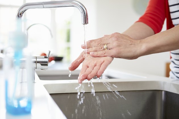 Close Up Of Woman Washing Hands In Kitchen Sink