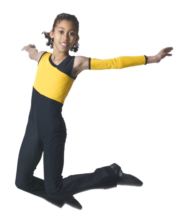an african american girl in a black and yellow dance outfit jumps through the air
