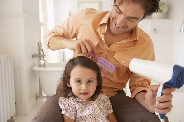 Father blowdrying daughter's (2-4) hair, close-up
