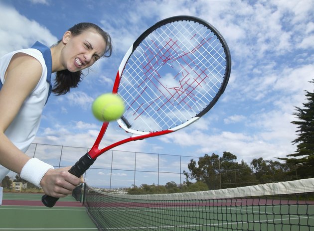 Woman holding tennis racket with hole in it and tennis ball in air
