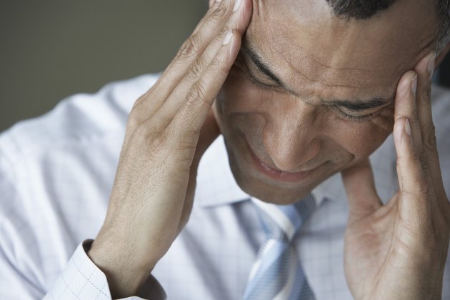 Business man holding head in hands close up elevated view