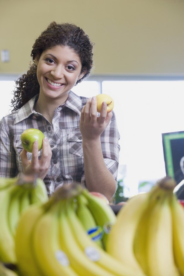 Mixed Race woman choosing apples at grocery store
