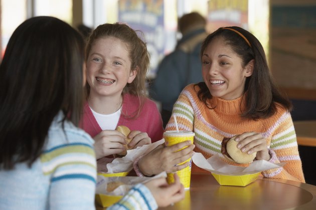 Three teenage girls sitting at a table and eating