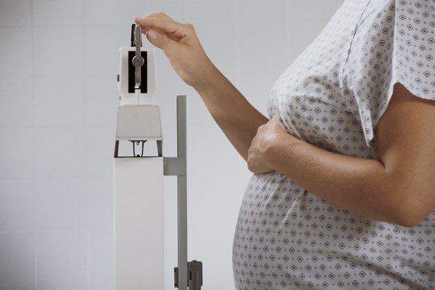 Pregnant woman weighing herself on hospital scale