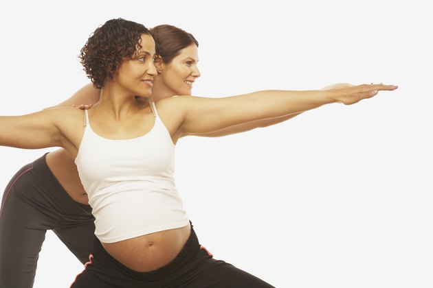 Yoga trainer assisting pregnant woman