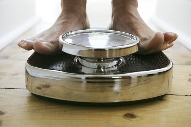 Man standing on weight scale, close-up, low section