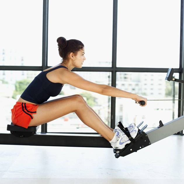 side profile of a young woman exercising on a rowing machine in a gym