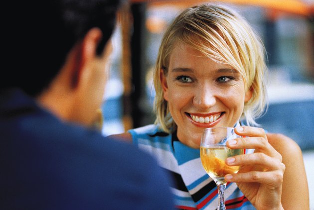 close-up of a woman holding a glass of wine and smiling at a man