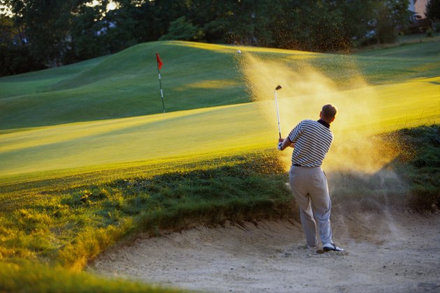 Man hitting golf ball out of sand trap