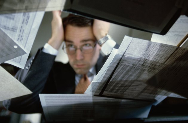 Low angle view of a businessman sitting at his desk holding his head