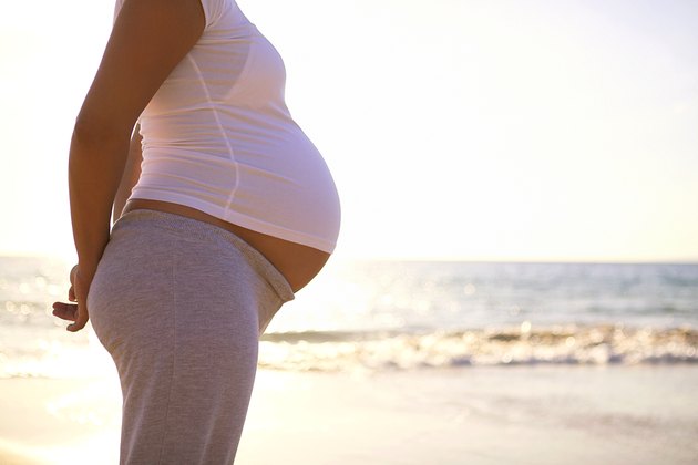 Torso of pregnant woman on beach