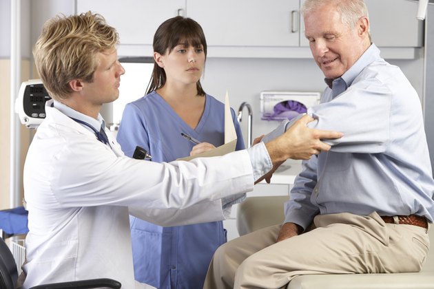 Doctor Examining Male Patient With Elbow Pain