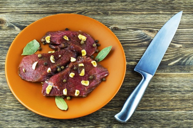 Marinated beef and spices on a ceramic plate.