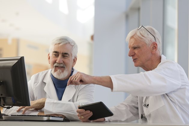 Two doctors discussing information on a computer and a tablet