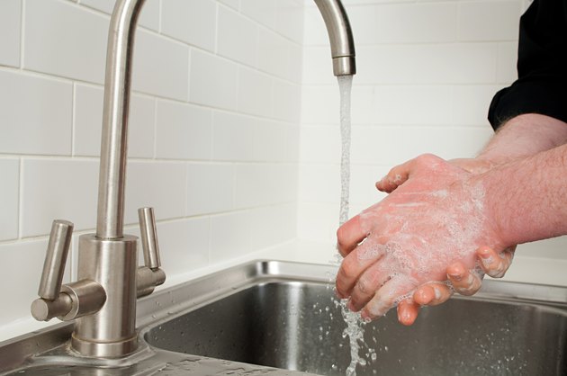 Man washing hands in kitchen sink