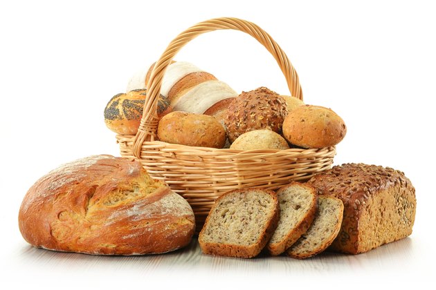 Loafs of bread and rolls in basket isolated on white
