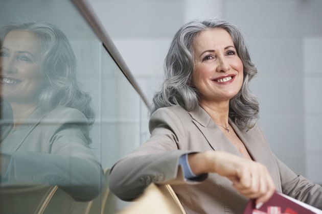 Mature businesswoman sitting in airport, smiling