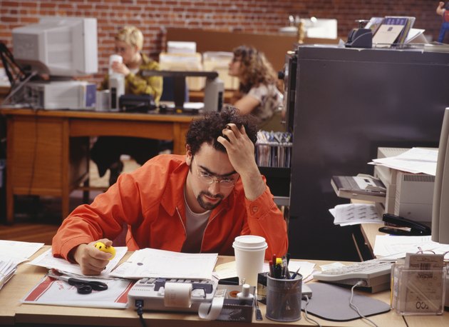 Man sitting at desk, supporting head with hand