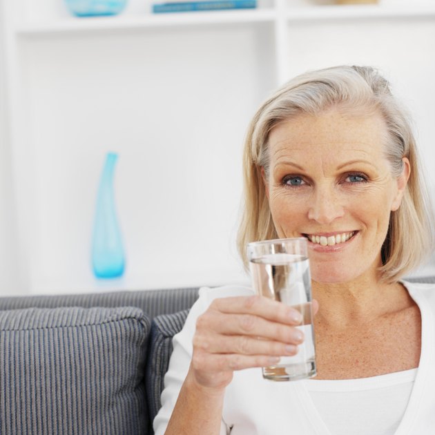 Close-up front view of mature woman holding glass of water