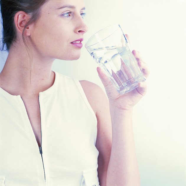 Woman holding glass of water looking away