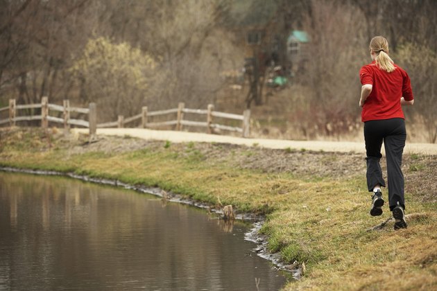 Rear view of a young woman jogging near a pond