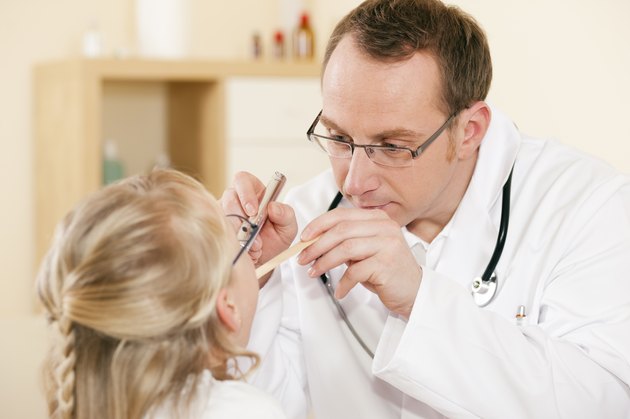 Pediatrician doctor examining throat of girl