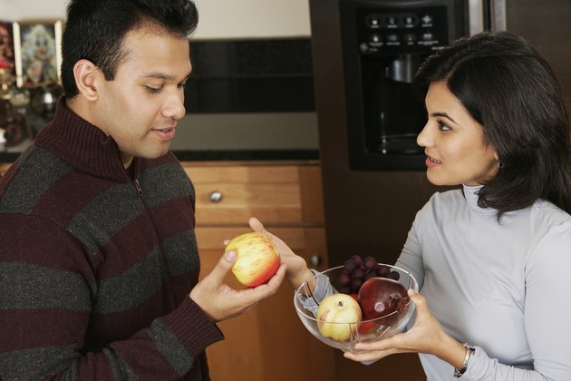 Side profile of a young woman giving apple to a young man