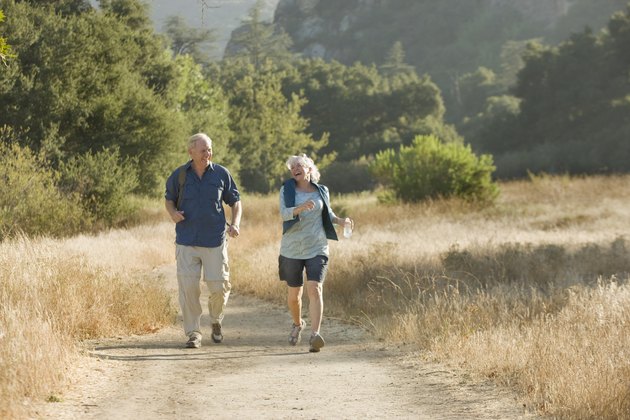 Mature couple walks down a nature trail.