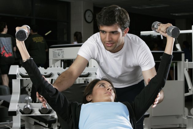 Young man teaching a young woman in a gym
