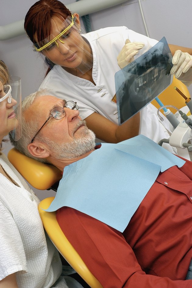 Two female dentists showing an X-Ray to a male patient
