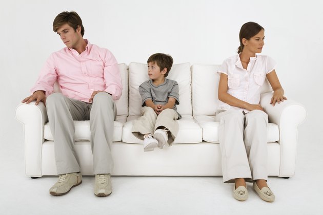 Boy sitting on couch with aloof parents