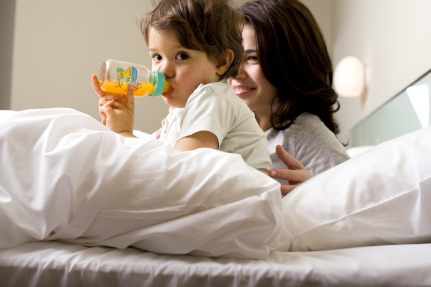 Mother and child drinking juice in bed