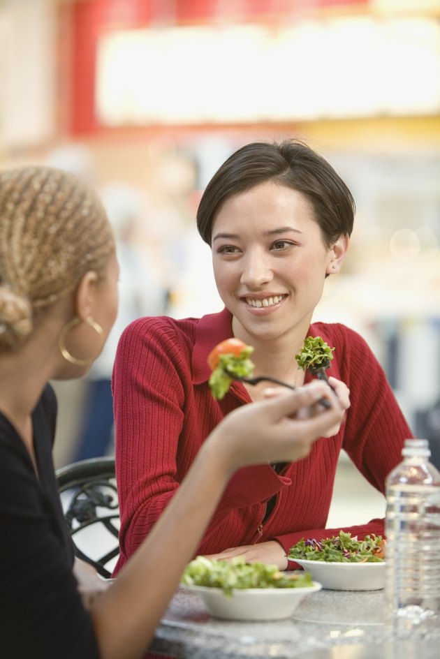 Mixed Race women eating salad