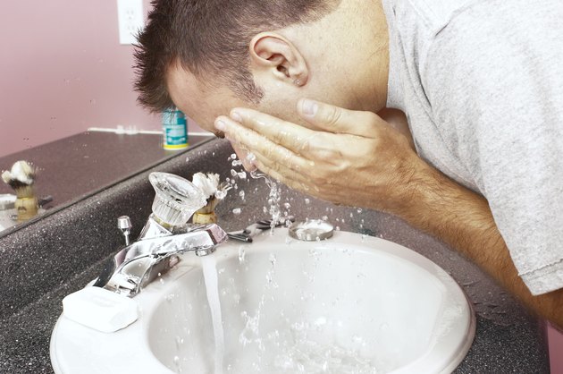 Man washing face at sink