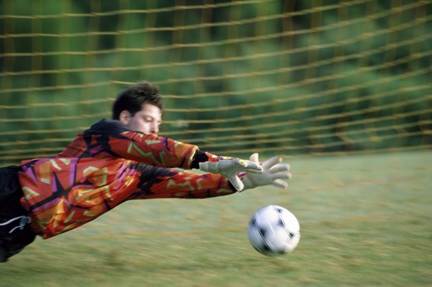 Goalie diving on a field to save the ball