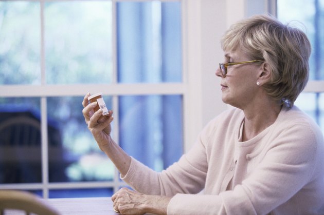 Senior woman reading the label on a pill bottle