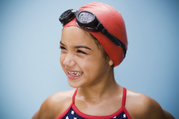 Hispanic girl in bathing suit with goggles and swim cap
