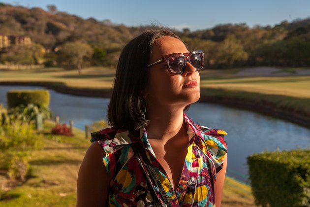 Young woman in sunglasses enjoying summer breeze at beach