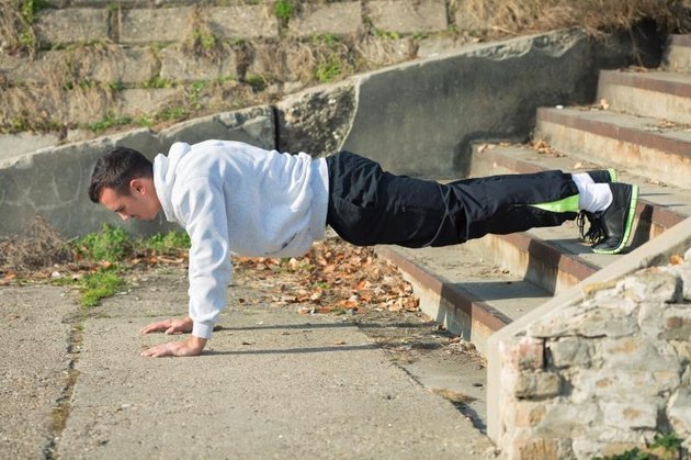 Attractive young man is exercising outdoors. He is doing push-ups on the staircase.