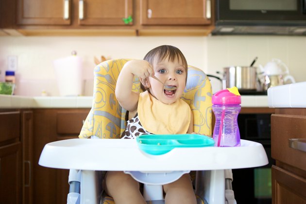 Little Girl Eating in High Chair